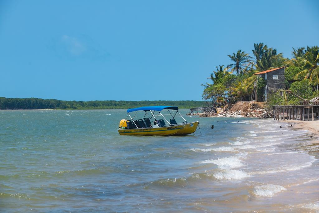 Lancha voadeira na praia de Caburé com coqueiros e mar cristalino